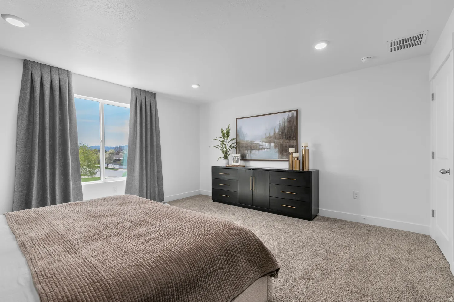 Brightly lit bedroom featuring recessed ceiling lighting, light-toned carpeting, a large window, and white walls