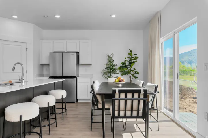 Open-concept kitchen and dining area featuring a sliding glass door, recessed lighting, wood-finish flooring, a kitchen island with seating, and stainless steel appliances