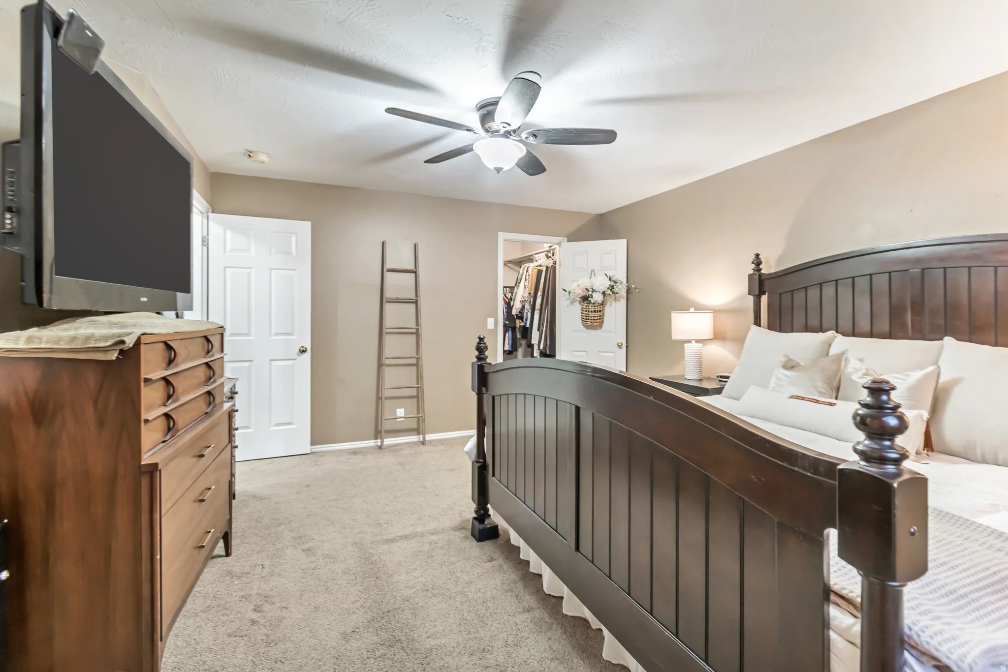 Carpeted bedroom featuring a ceiling fan, neutral wall tones, and a closet with bifold doors