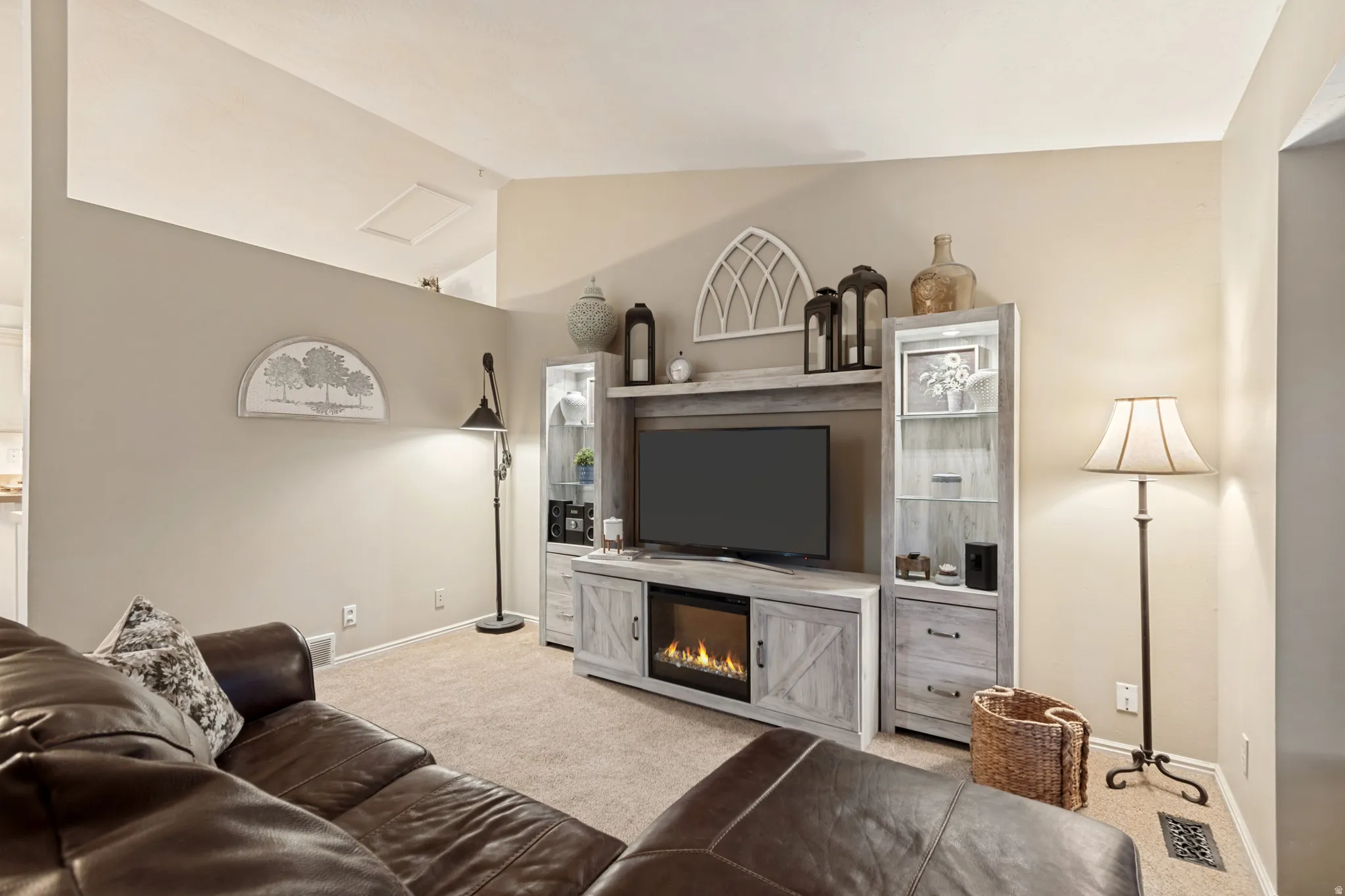 Living area featuring carpet flooring, an entertainment center with an integrated electric fireplace, and a vaulted ceiling