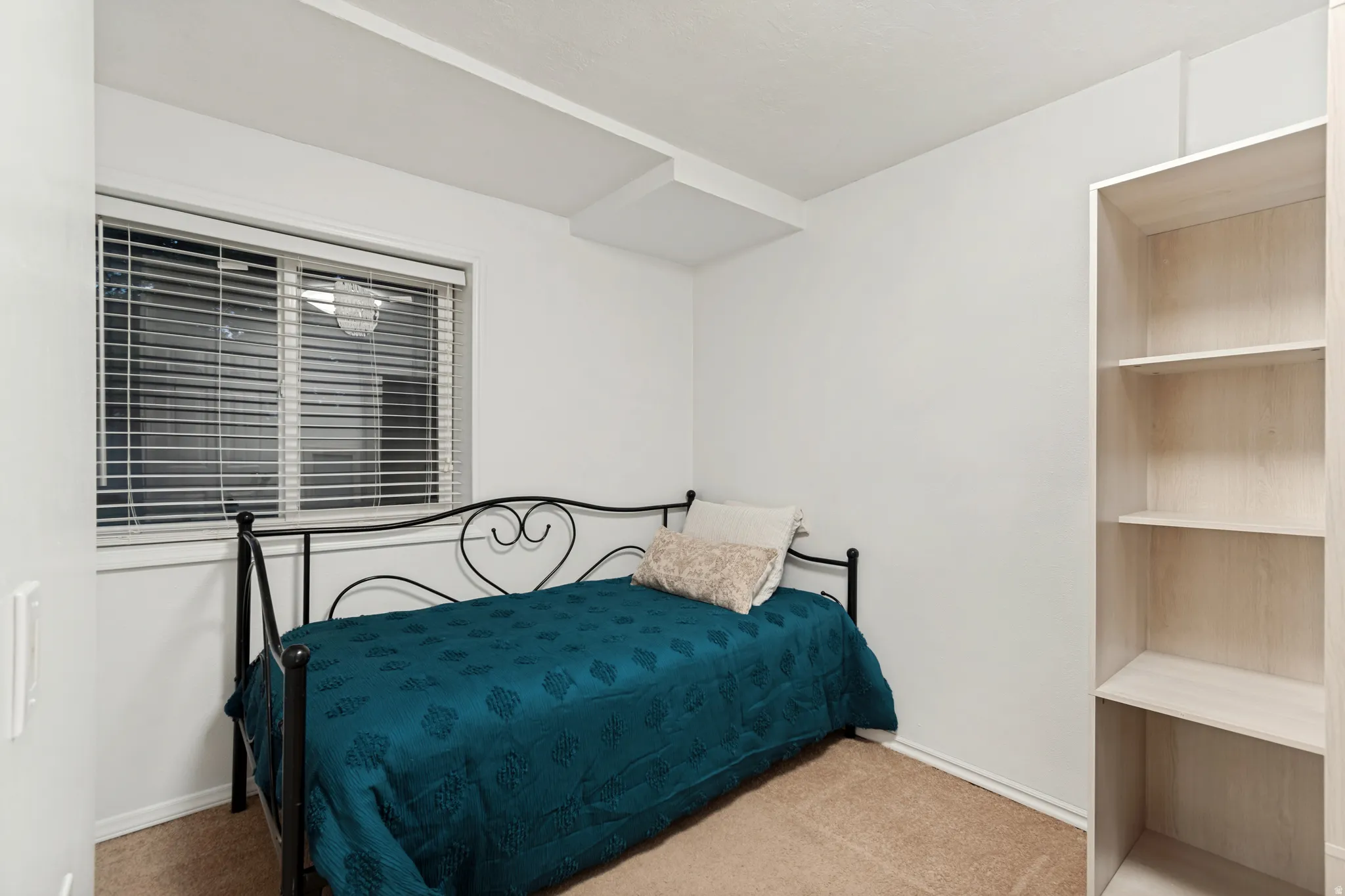 Carpeted room with a window featuring horizontal blinds