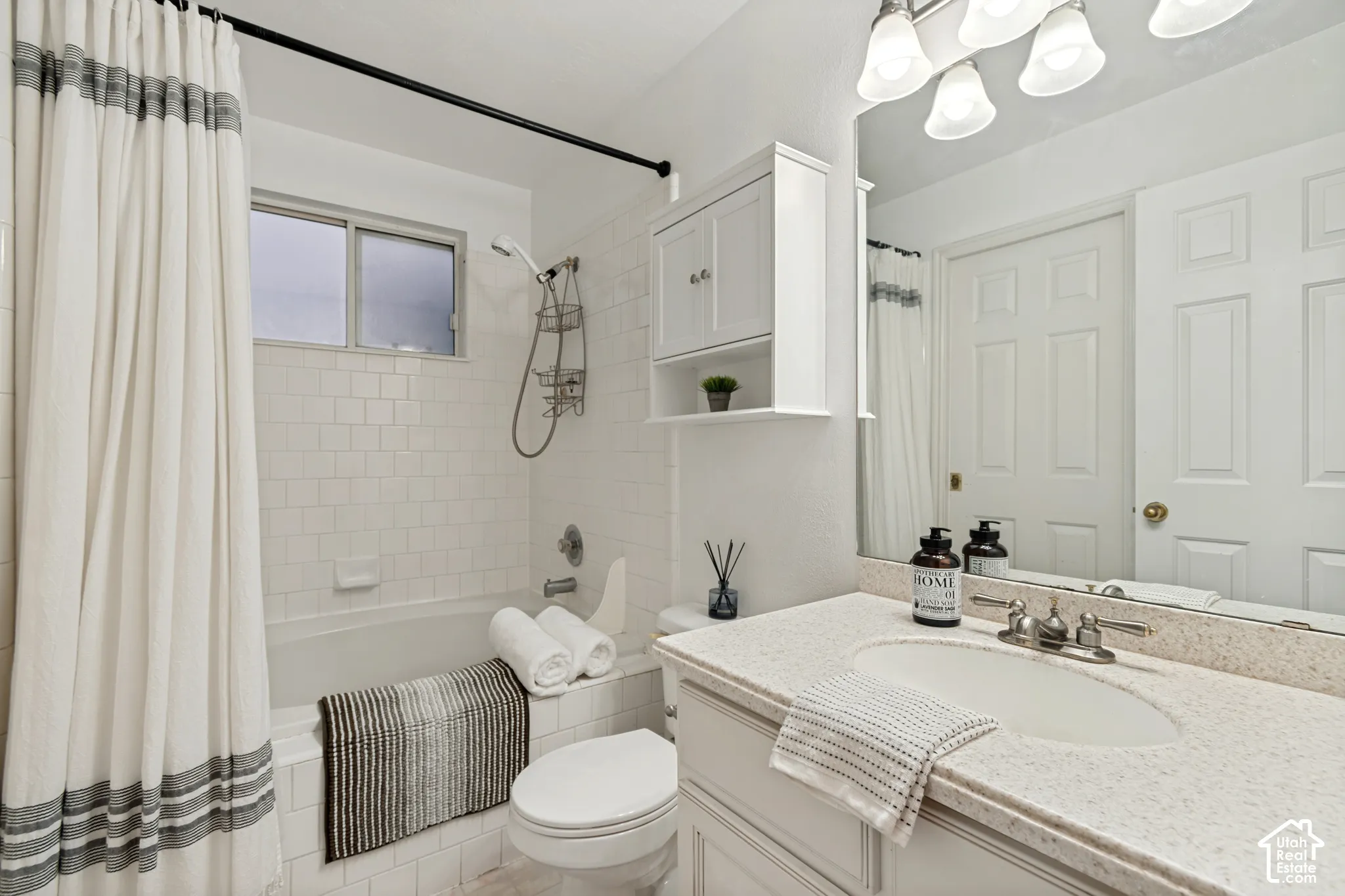 Bathroom featuring a tub/shower combination with subway tile surround, a built-in window, and a vanity with a light-toned countertop and integrated sink