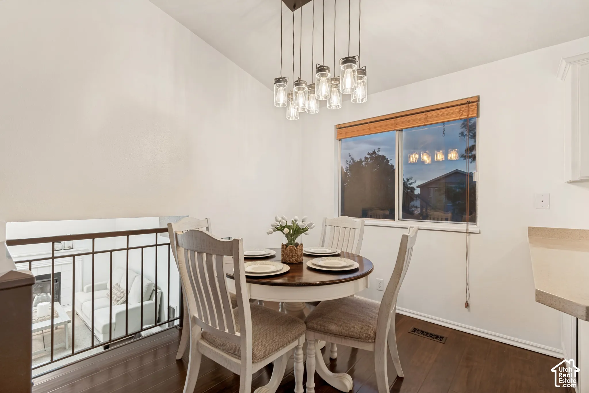 Dining area featuring dark wood-finish flooring, a contemporary multi-light pendant fixture, and a window with wood blinds
