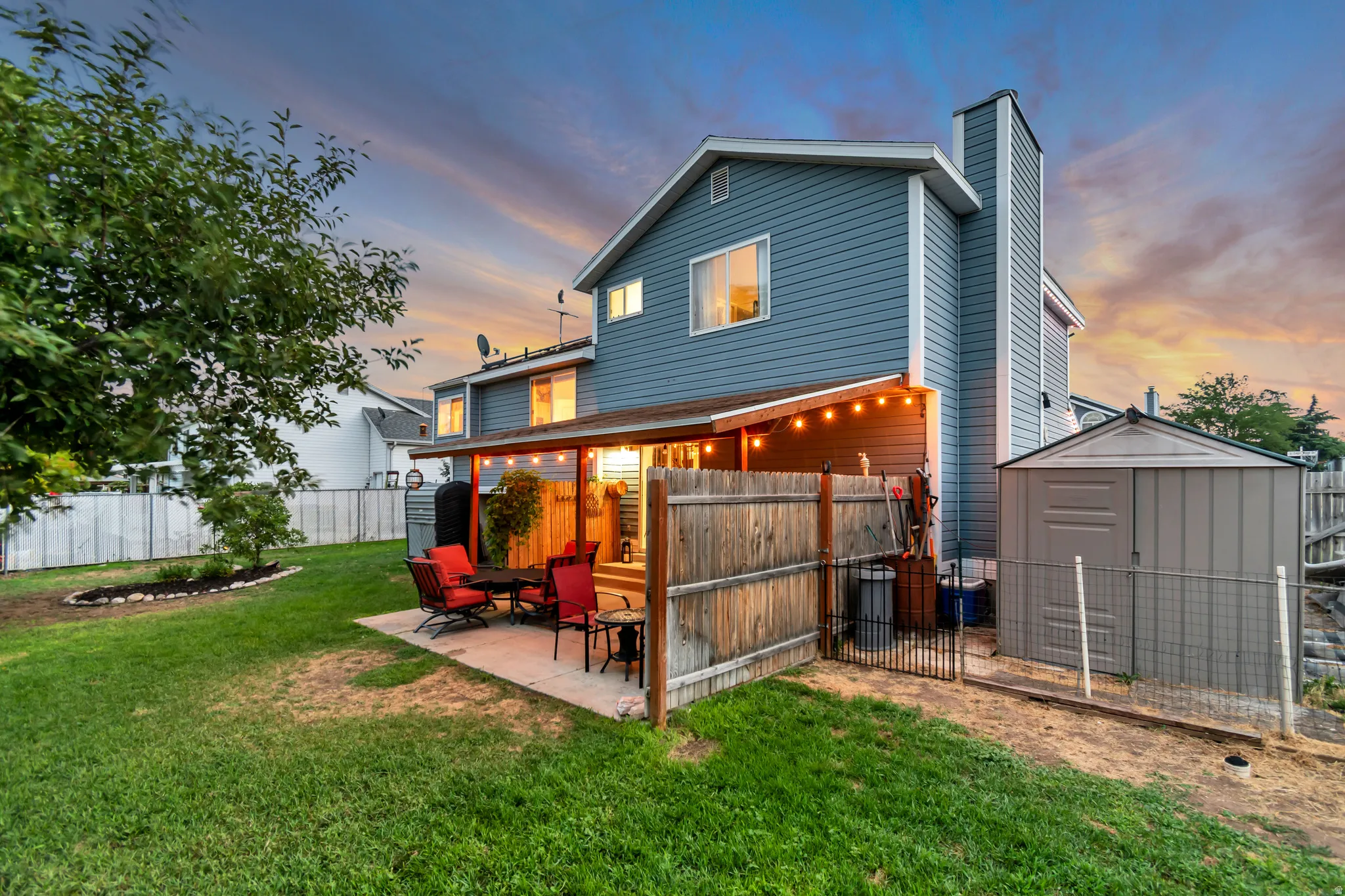 Expansive backyard featuring a covered patio, concrete slab, established lawn, and a storage shed