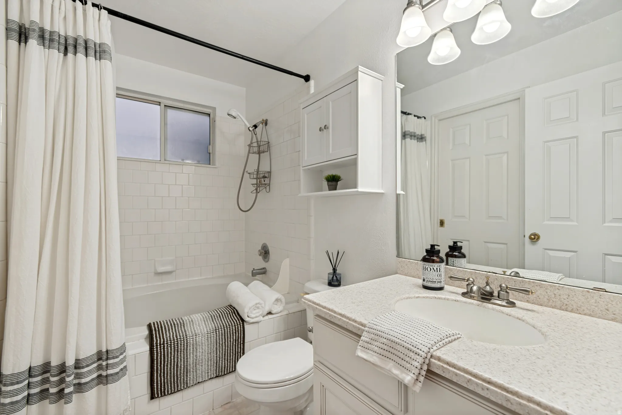 Bathroom featuring a tub/shower combination with subway tile surround, a built-in window, and a vanity with a light-toned countertop and integrated sink