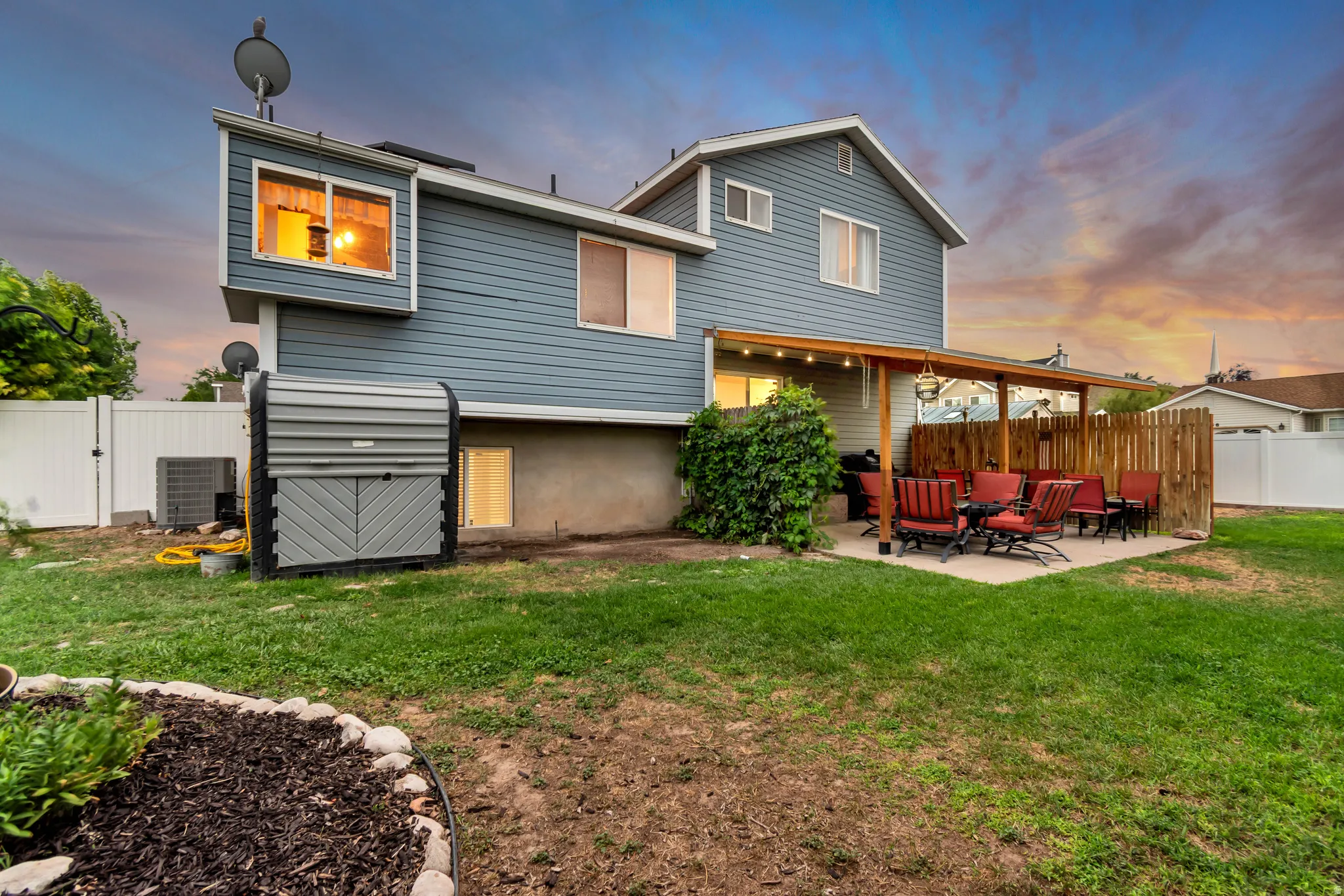 Expansive backyard featuring a covered patio, privacy fence, mature landscaping, and a well-maintained lawn