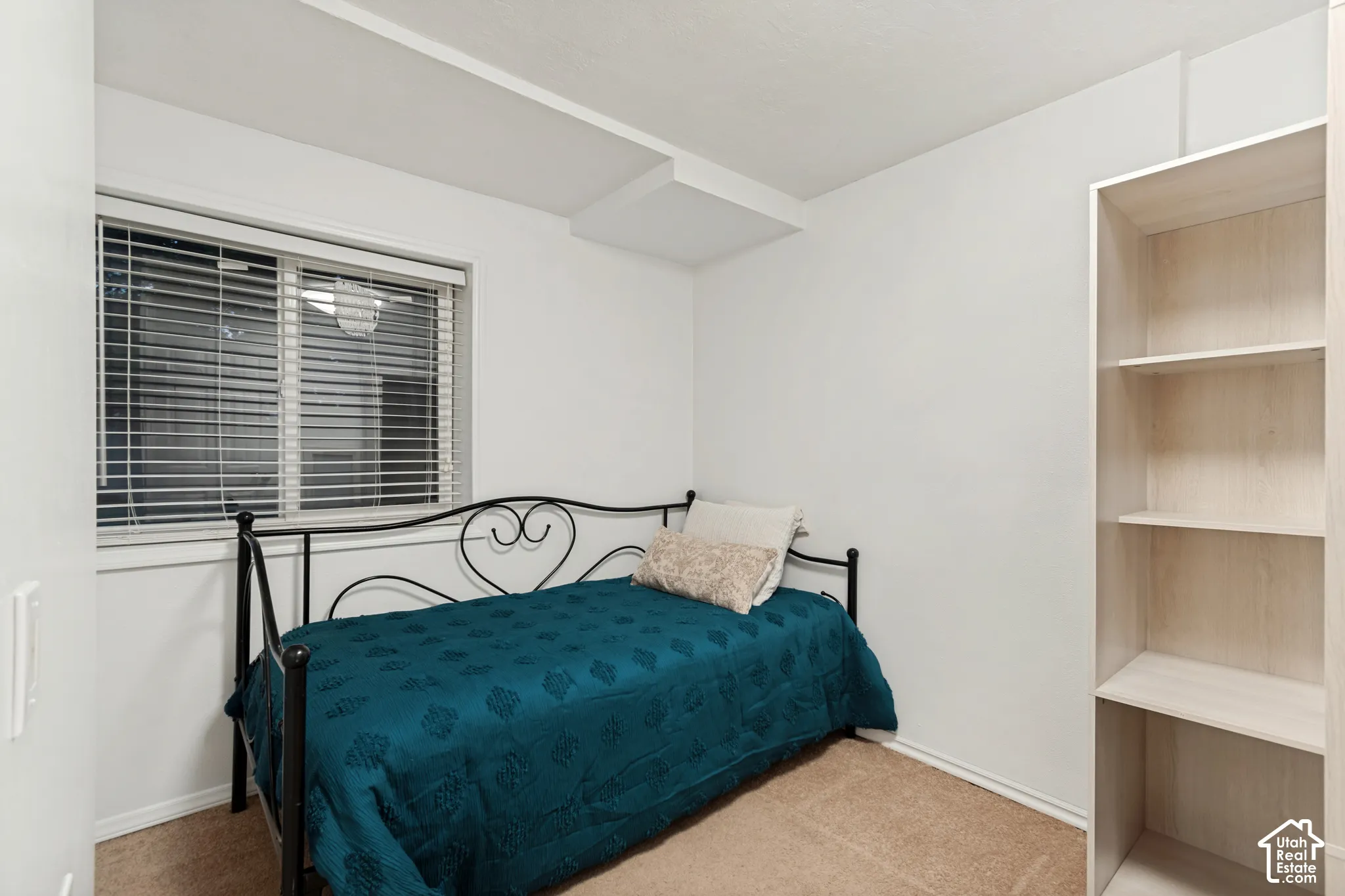 Carpeted room with a window featuring horizontal blinds