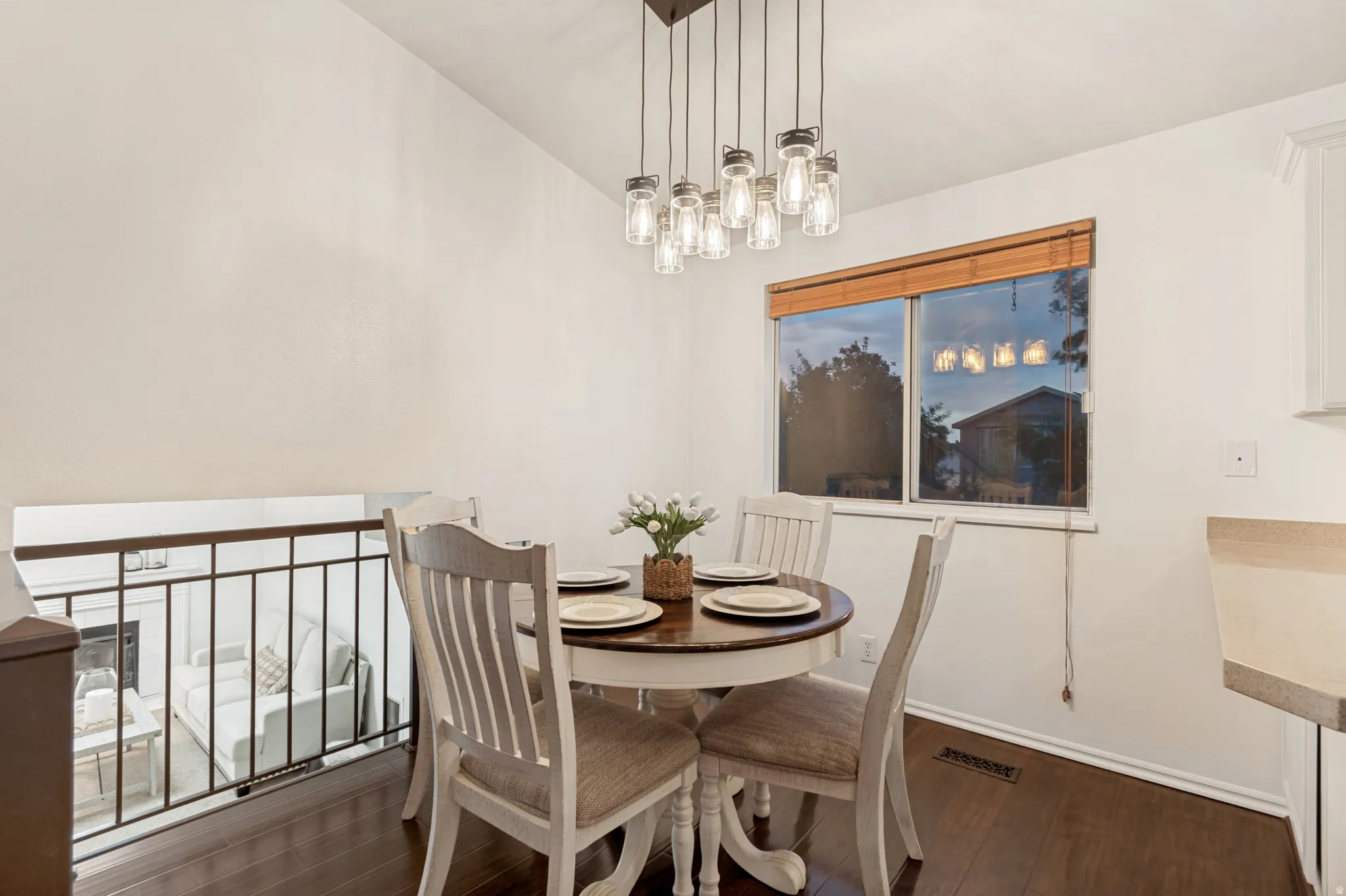 Dining area featuring dark wood-finish flooring, a contemporary multi-light pendant fixture, and a window with wood blinds