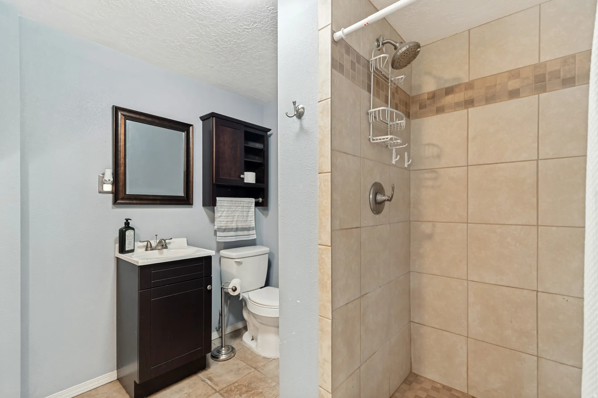Bathroom featuring a dark wood-finish vanity with a white countertop, a framed mirror, and built-in wall cabinetry
