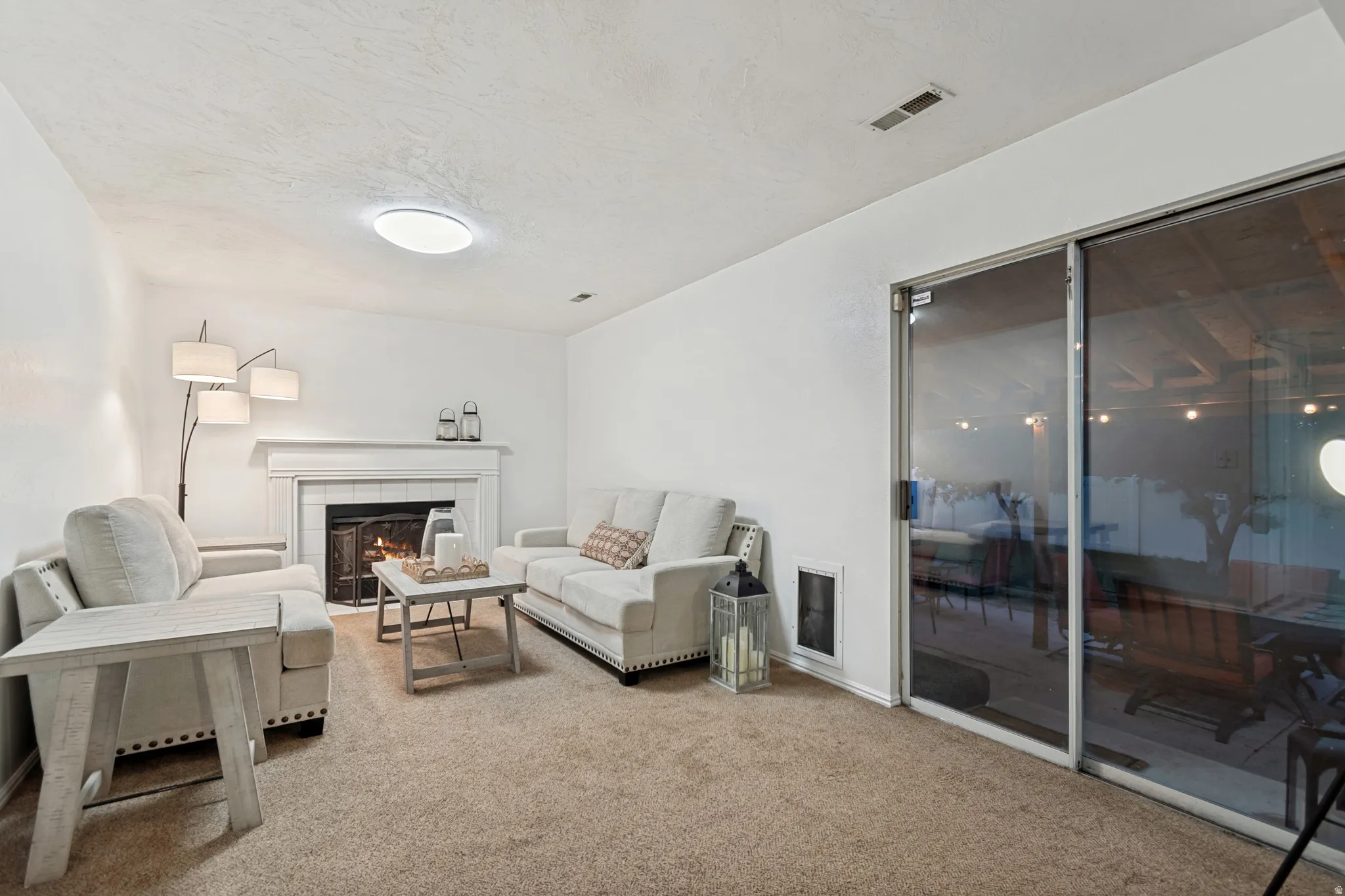 Living area featuring a fireplace with a white mantel, carpet flooring, and a sliding glass door