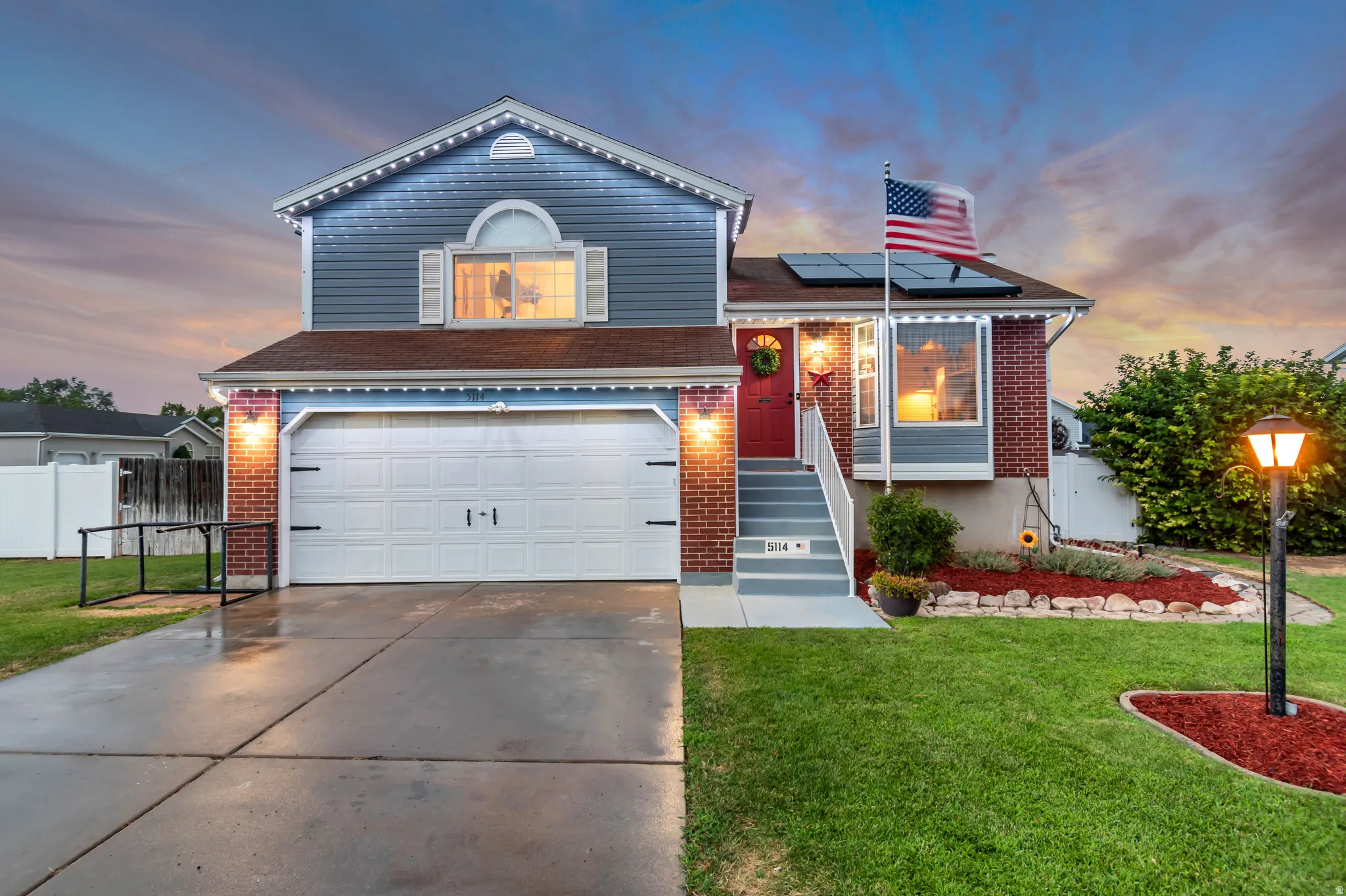 Two-story residence featuring a two-car garage, red brick accents, and light blue siding