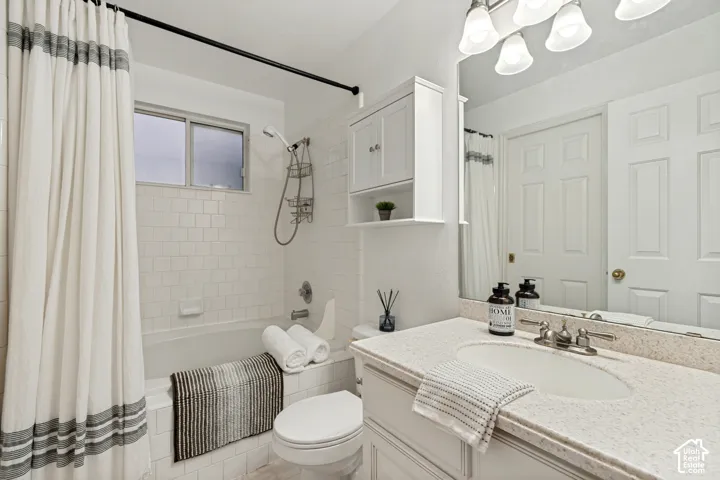 Bathroom featuring a tub/shower combination with subway tile surround, a built-in window, and a vanity with a light-toned countertop and integrated sink