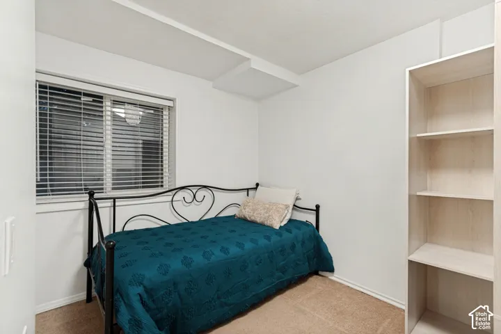 Carpeted room with a window featuring horizontal blinds