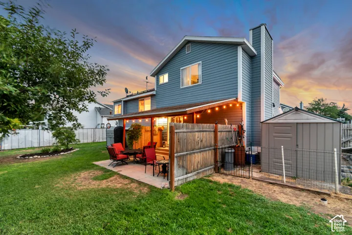 Expansive backyard featuring a covered patio, concrete slab, established lawn, and a storage shed