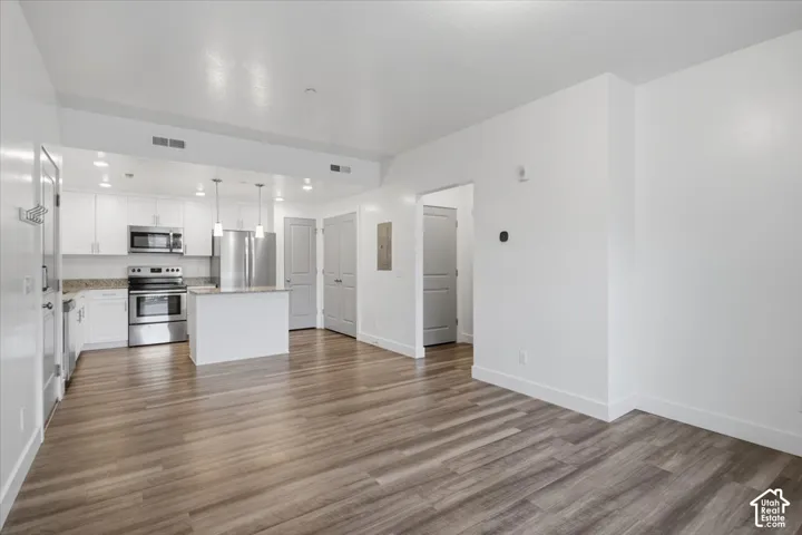 Open-concept living area with wood-finish flooring, recessed lighting, and white baseboards