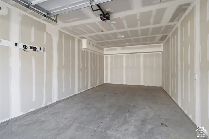 Spacious garage featuring a concrete floor, high ceilings, exposed drywall, and an overhead door mechanism