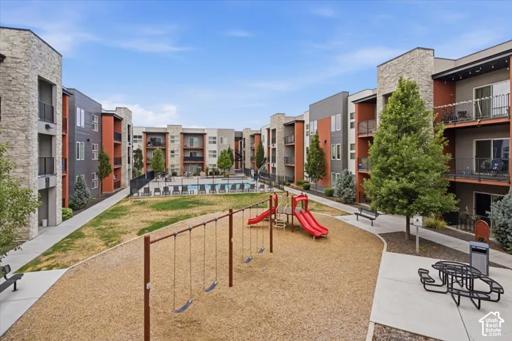 Ground-level amenity space featuring a children's play area with swings and slides, a picnic table, and a community pool
