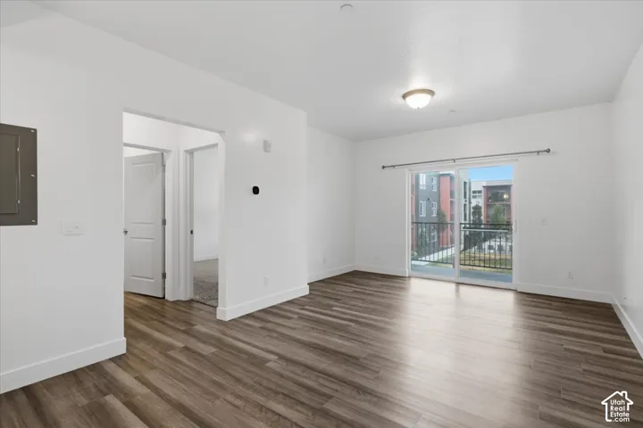 Open living space featuring wood-finish flooring, white baseboards, and a glass sliding door to an outdoor balcony