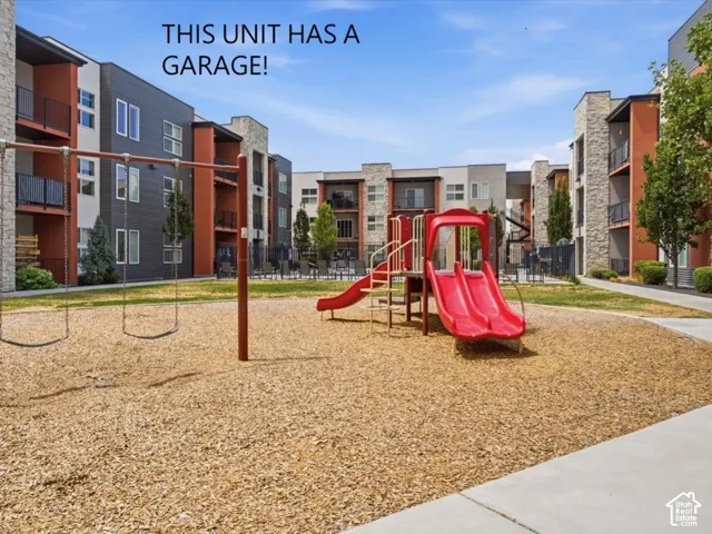 Outdoor playground with wood chip ground cover, swings, and a red slide structure
