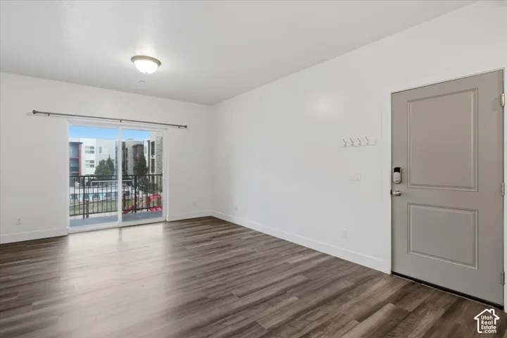 Spacious living area featuring wood-finish flooring, white baseboards, and a contemporary ceiling light fixture