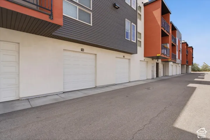 Multi-story building featuring white garage doors and a paved drive