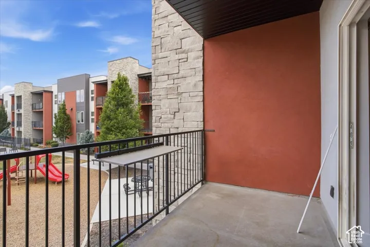 Balcony with concrete flooring and a black metal railing, featuring an integrated ledge