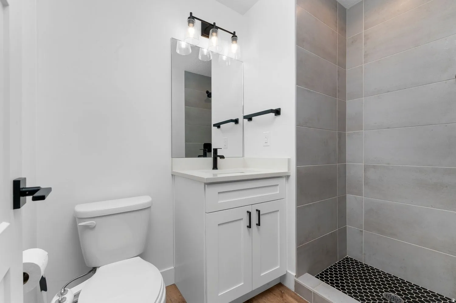 Modern bathroom featuring a white vanity with a rectangular undermount sink, quartz countertop, and matte black faucet