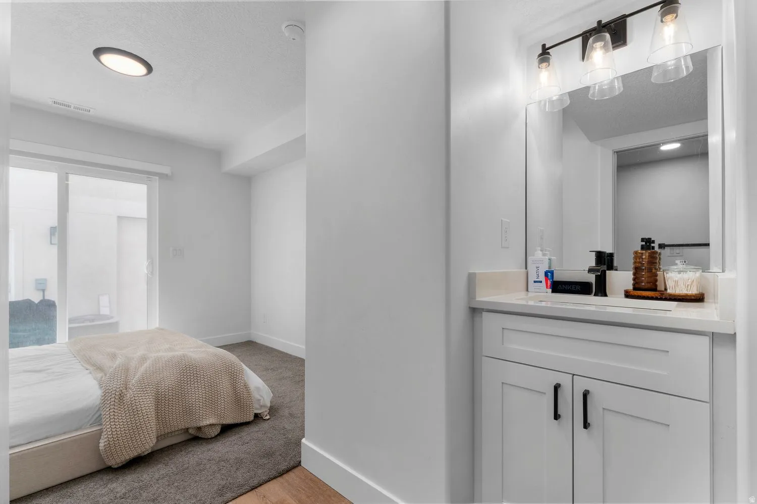 Contemporary vanity with white cabinetry, matte black hardware, and a light-toned countertop