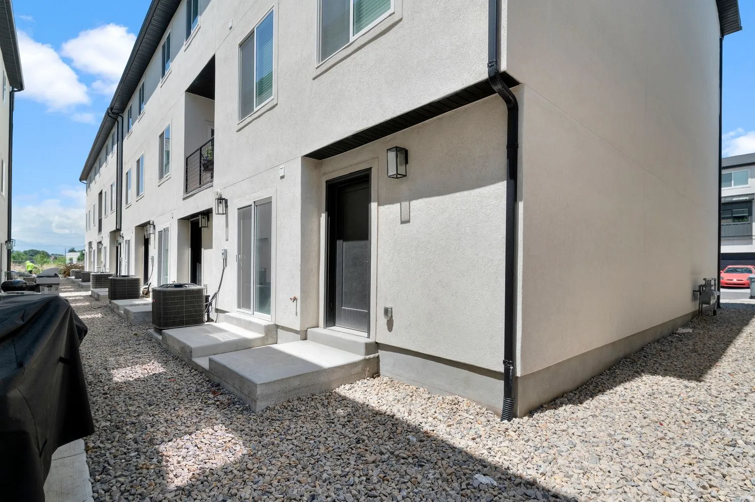 Stucco exterior featuring black downspouts and exterior lighting