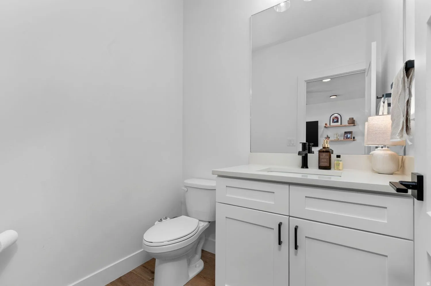 White shaker vanity with black hardware, complementing a white countertop and rectangular undermount sink