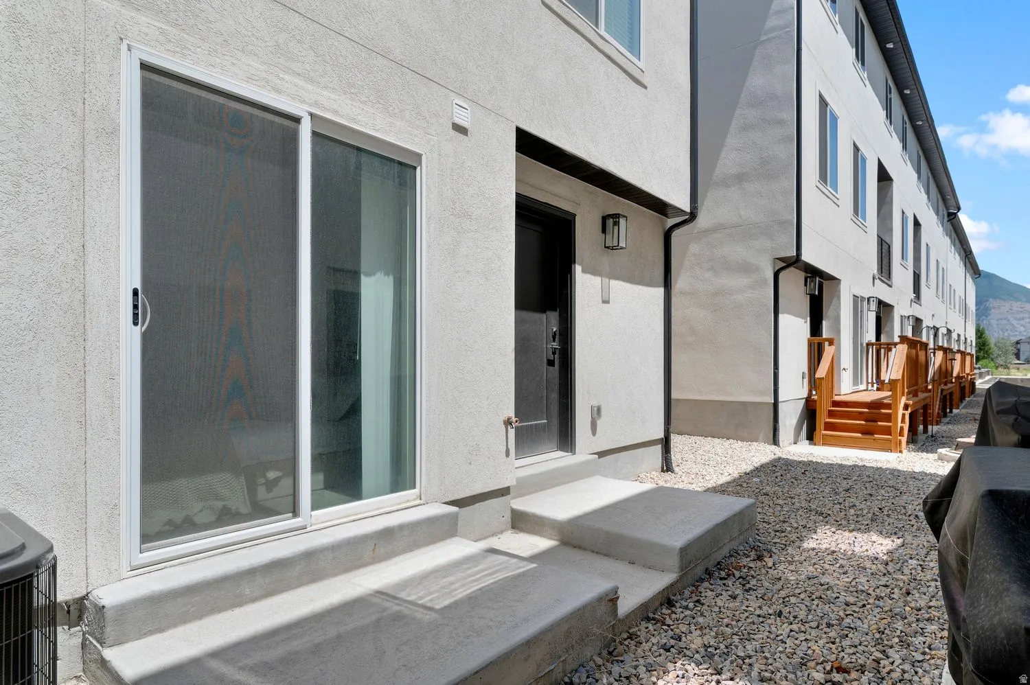 Stucco exterior with a sliding glass patio door, entry door, and concrete steps