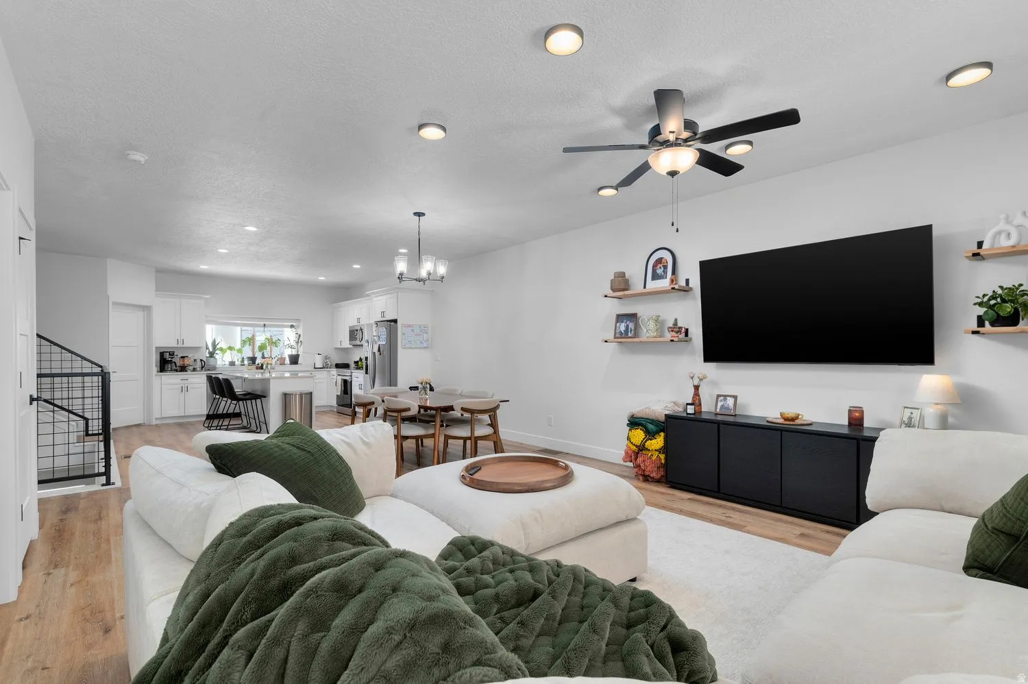 Open-concept living space featuring wood-finish flooring, recessed lighting, and a ceiling fan with integrated lighting