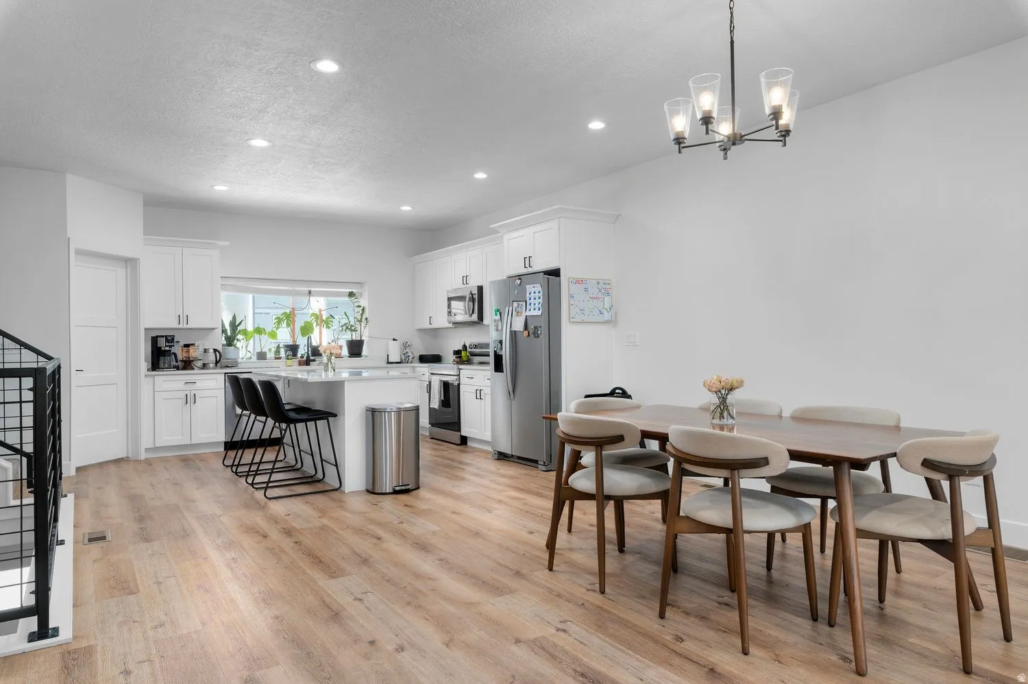Kitchen and dining area featuring wood-finish flooring, recessed lighting, and a modern chandelier