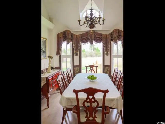 Dining area featuring vaulted ceilings, a decorative chandelier, and light wood-finish flooring
