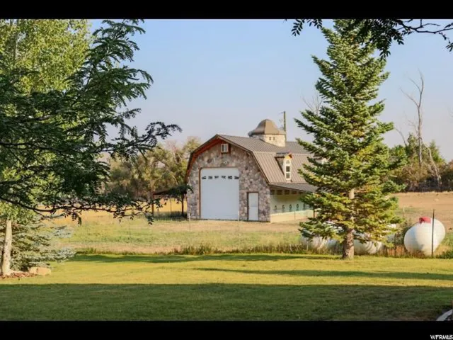 Stone-clad barn structure featuring a metal gambrel roof and a cupola