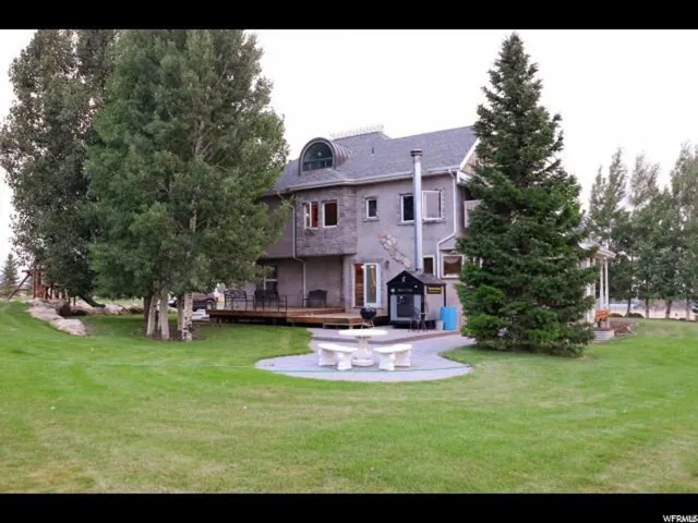 Expansive green lawn with mature trees and a two-story gray stucco exterior