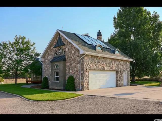 Stone exterior construction featuring solar panels, a two-car garage, and a covered porch