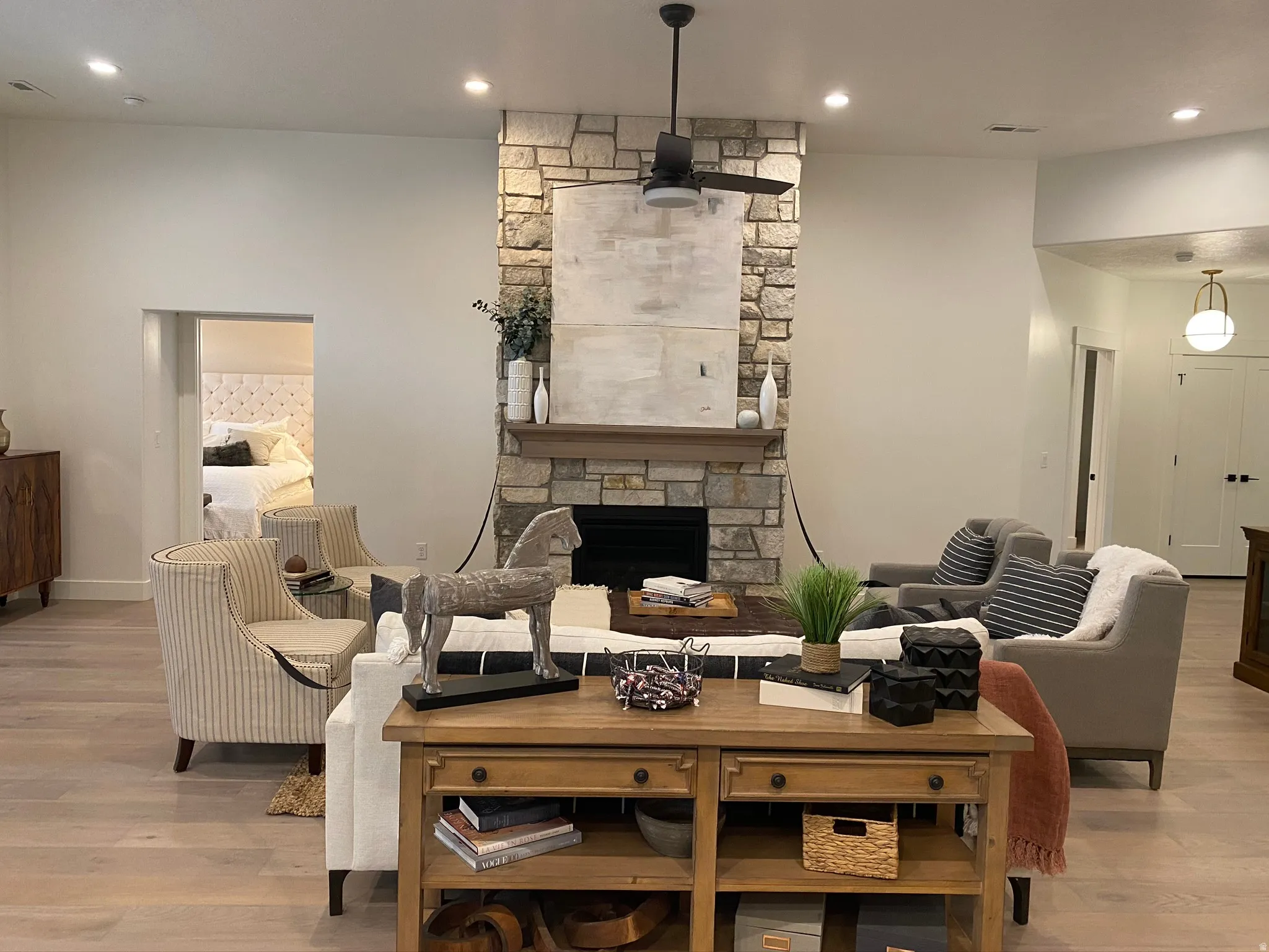 Stone-clad fireplace with wood mantel and hearth, complemented by a ceiling fan with integrated lighting