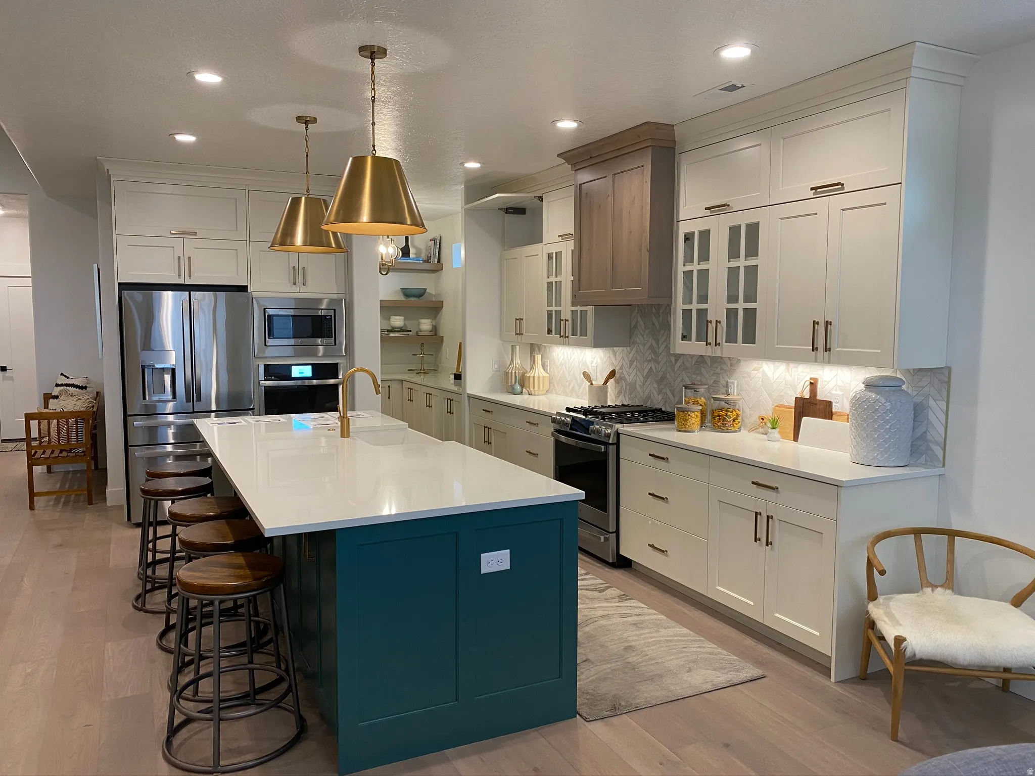 Spacious kitchen featuring a large island with a white countertop, two-tone cabinetry, stainless steel appliances, and wood-finish flooring