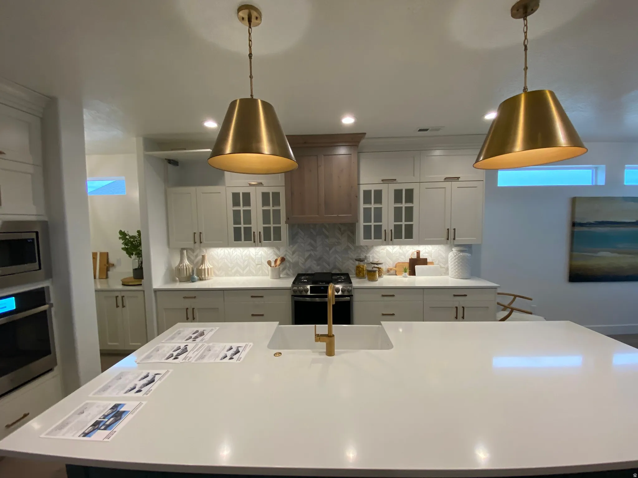Expansive kitchen island with an integrated sink and gold-finish faucet, complemented by two large gold-tone pendant lights