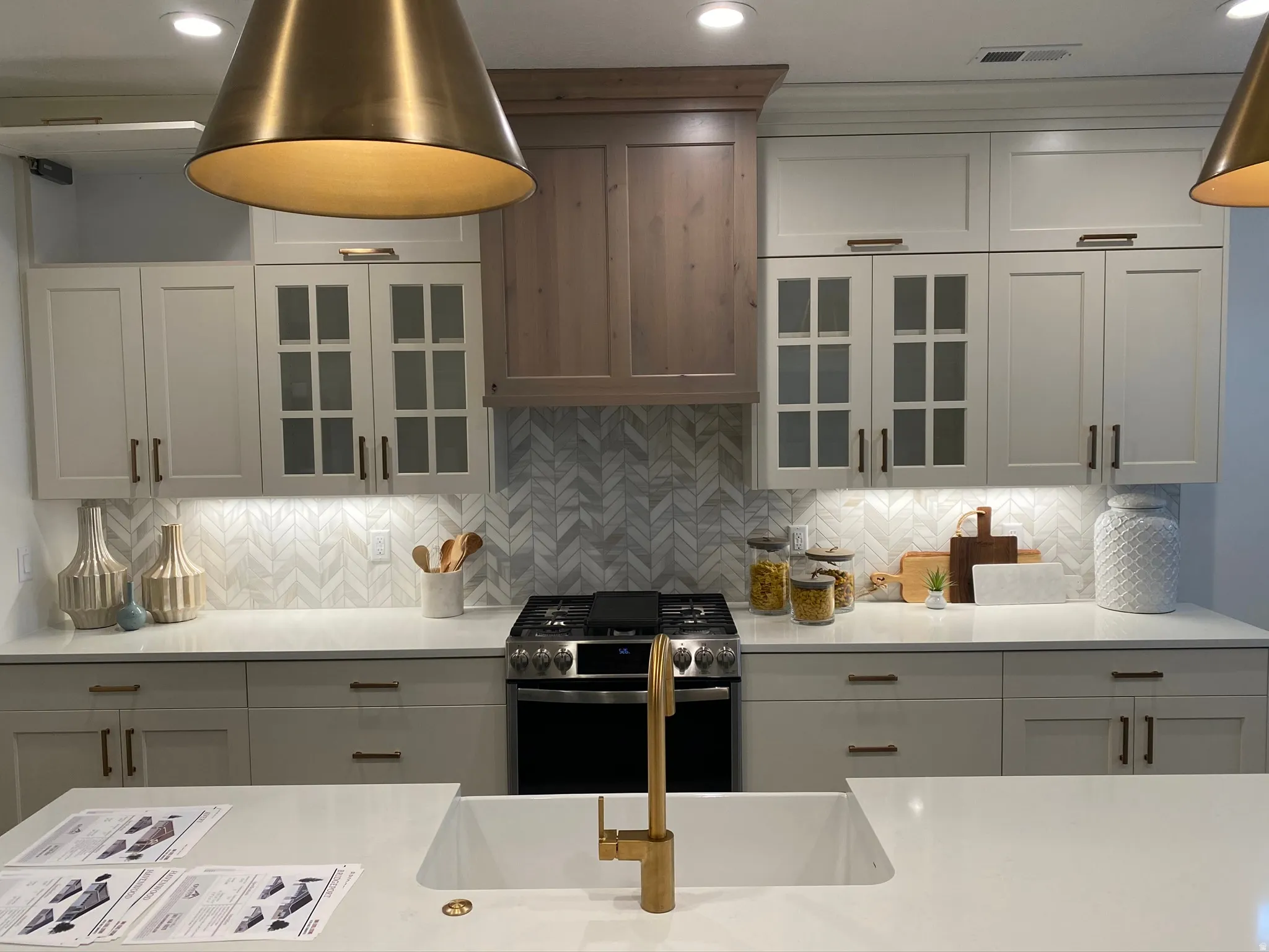 Contemporary kitchen featuring light-toned cabinetry, a chevron-patterned backsplash, and integrated under-cabinet lighting