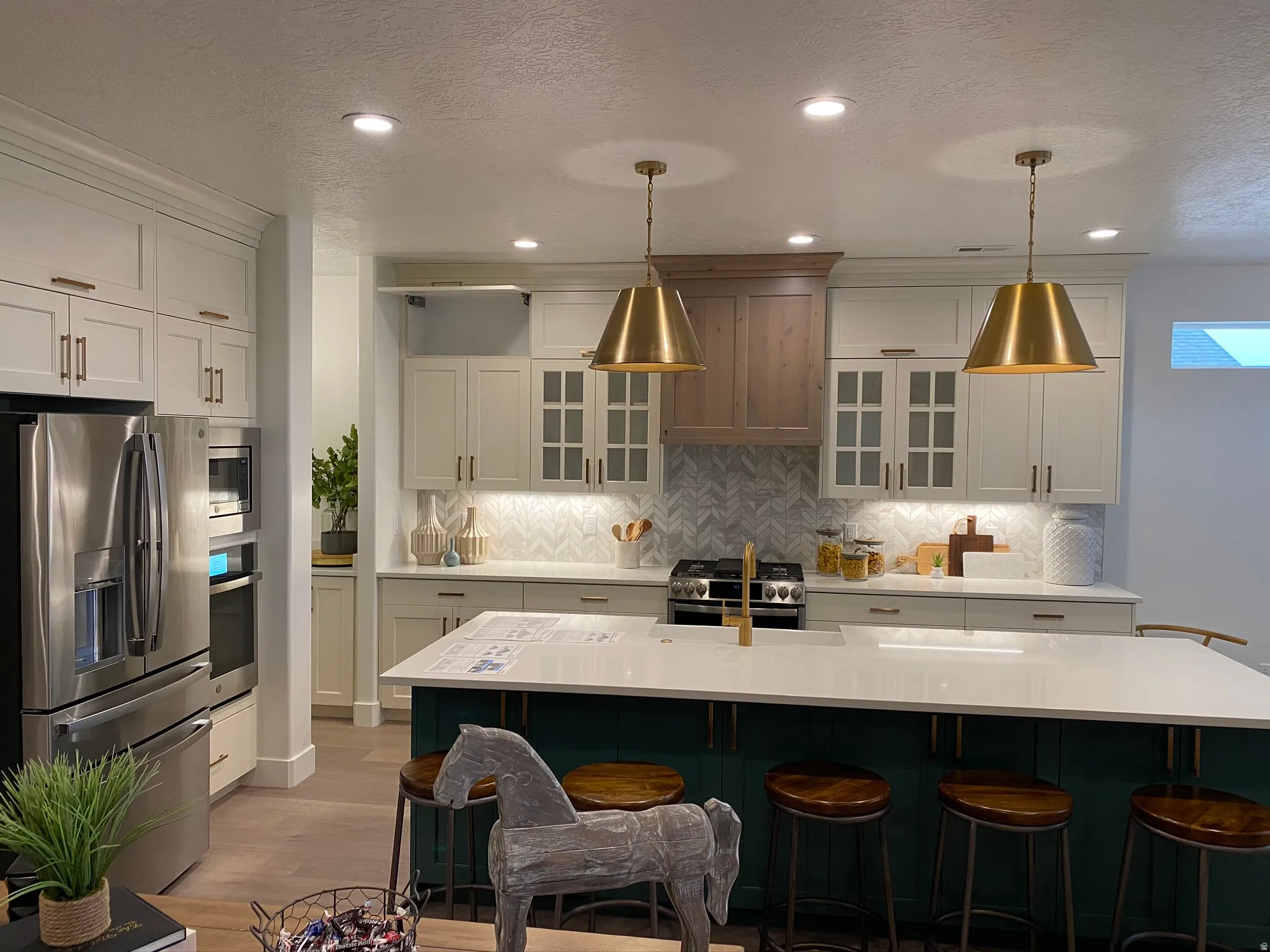 Contemporary kitchen featuring a large island with seating, stainless steel appliances, and a chevron pattern backsplash