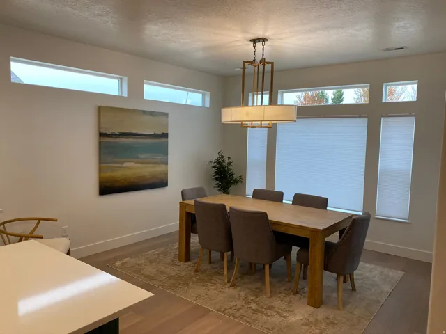 Dining area featuring a contemporary linear chandelier, multiple transom windows, and expansive main windows with blinds