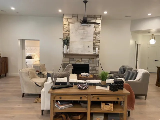Stone-clad fireplace with wood mantel and hearth, complemented by a ceiling fan with integrated lighting