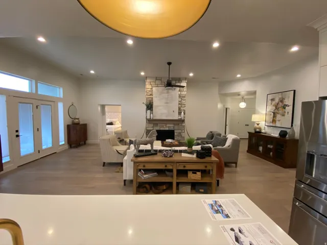 Spacious living area featuring light wood-finish flooring, a stone-clad fireplace with a wood mantle, and recessed lighting
