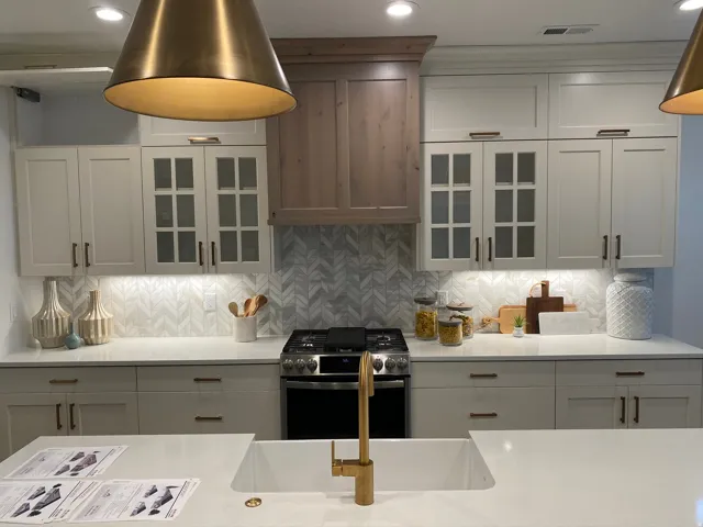 Contemporary kitchen featuring light-toned cabinetry, a chevron-patterned backsplash, and integrated under-cabinet lighting