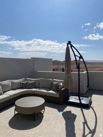 Expansive rooftop patio featuring a concrete surface, low perimeter walls, and distant mountain scenery