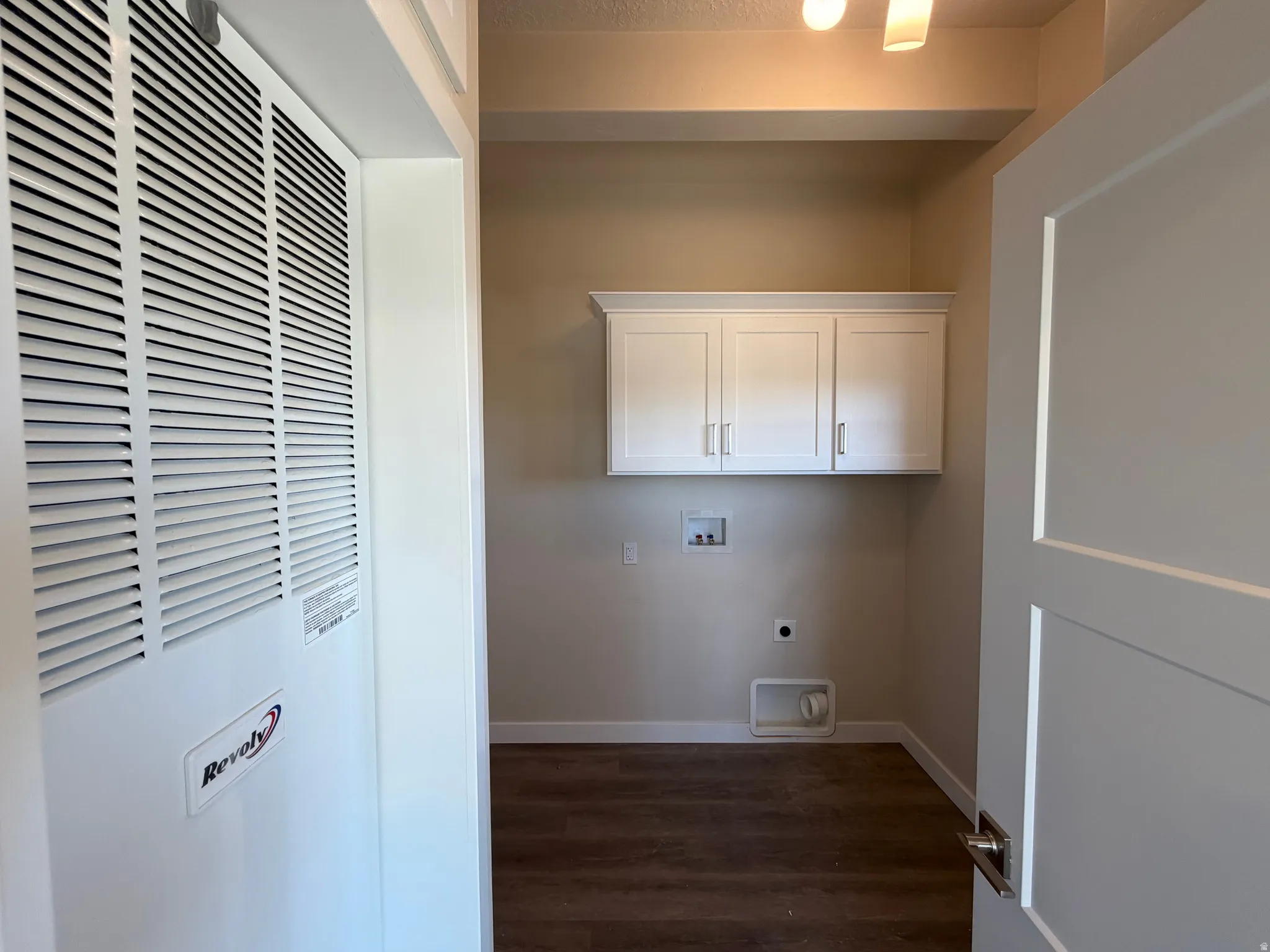 Utility area featuring white overhead cabinetry, wood-finish flooring, and neutral wall tones