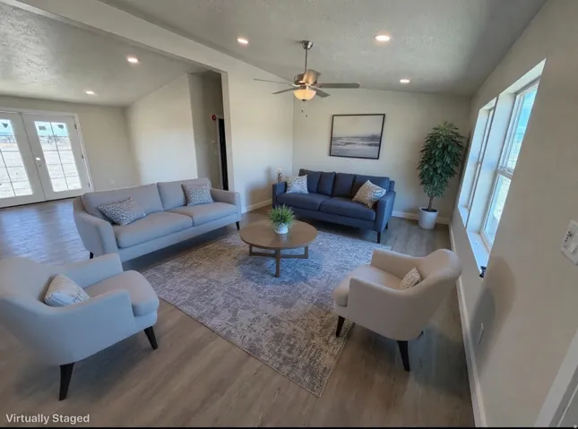 Spacious living area featuring wood-finish flooring, recessed lighting, and a ceiling fan