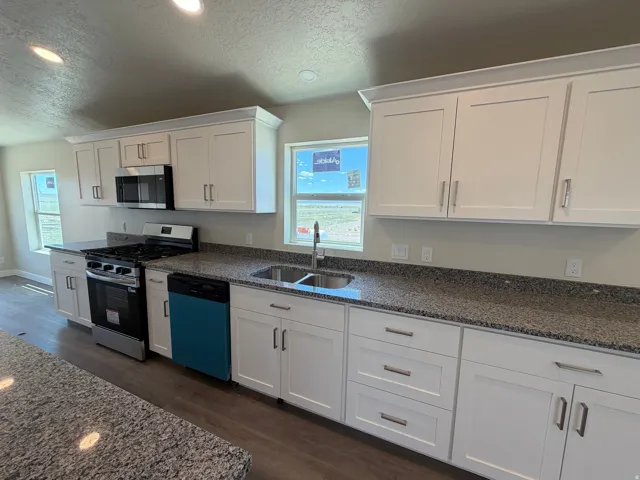 Kitchen featuring white shaker cabinetry, stainless steel appliances, granite countertops, and wood-finish flooring